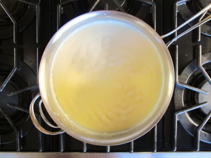 Adding milk to a roux in a skillet.