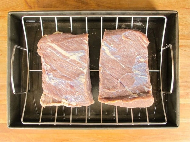 Brisket set on a rack in a roasting pan.