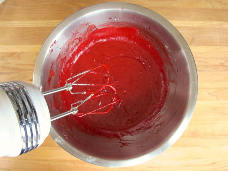 Adding red food coloring to cake batter.