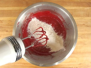 Adding flour to wet cake batter.