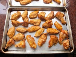 Marinated chicken wings spread out on a baking sheet.