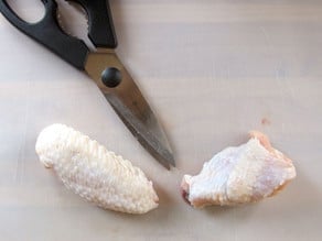 Separating the two chicken wing parts.