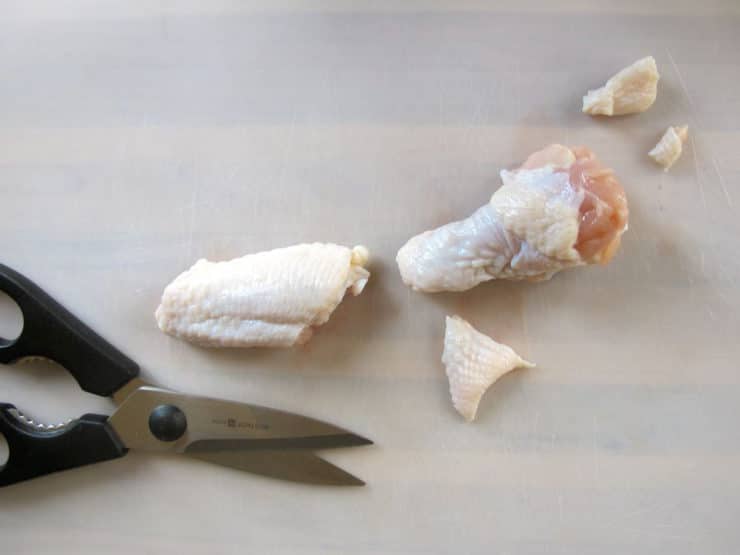 Trimming excess fat and skin from chicken wings.