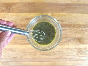 Whisking salad dressing in a small bowl.