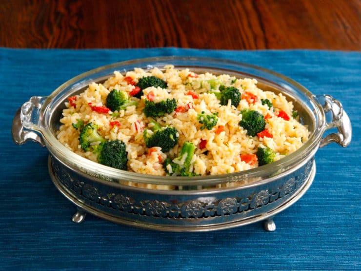 Delicious Zesty Broccoli Cheddar Rice served in a beautiful casserole dish, placed on top of a blue tablecloth