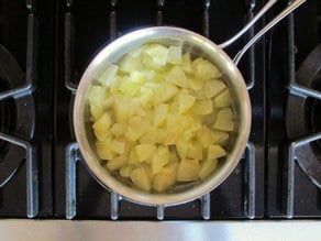 Peeled, diced apples simmering in a saucepan.