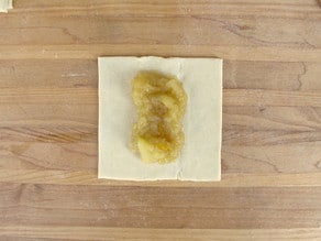 Placing apple filling in the center of puff pastry square.