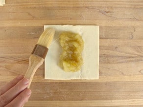 Brushing puff pastry with water to seal.