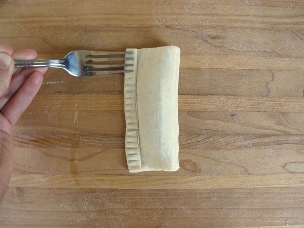 Sealing edges of pastry with a fork.