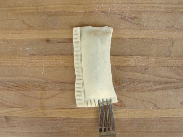 Sealing edges of pastry with a fork.