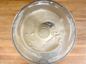 Blending tahini paste, water, lemon juice and salt in a food processor.