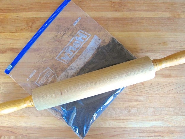 Crushing chocolate cookies in a bag with a rolling pin.
