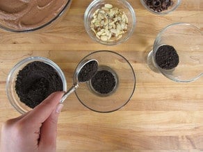 Adding crushed cookies to parfait cups.