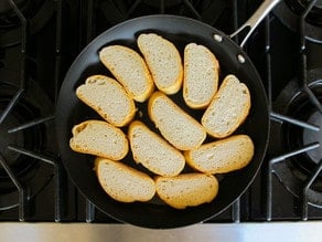 Toasting sliced baguette in a skillet.