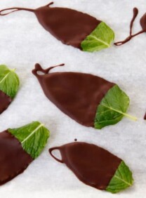 Dark chocolate-covered fresh mint leaves on parchment paper