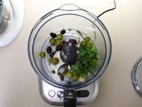 Overhead shot of a food processor filled with olive tapenade ingredients.