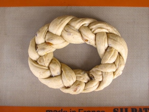 Braided dough circle set on a lined baking sheet.