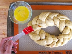 Brushing egg wash over a braided loaf.