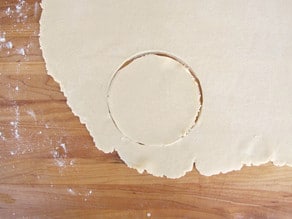 Cutting small circles out of rolled dough.