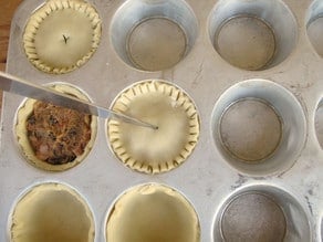 Cutting a vent in the top of mini pies.