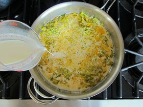 Adding milk to stockpot of potato leek soup.