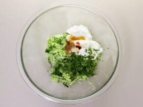 Horizontal shot - glass mixing bowl filled with cucumber raita ingredients.