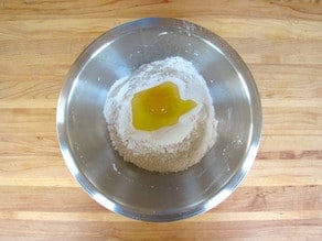 Egg cracked into a well in dry ingredients.