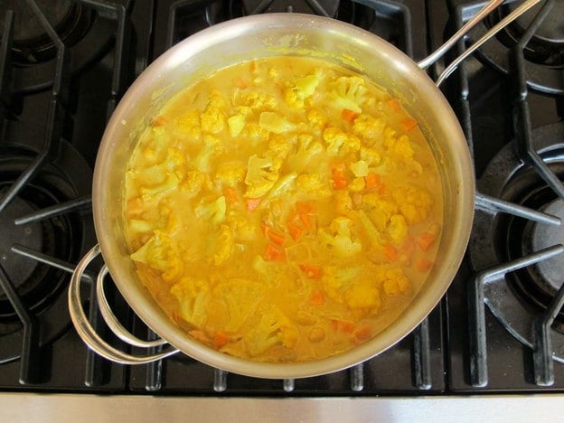 Coconut milk added to curry in saucepan.