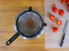 Straining pulp from fresh tomatoes.