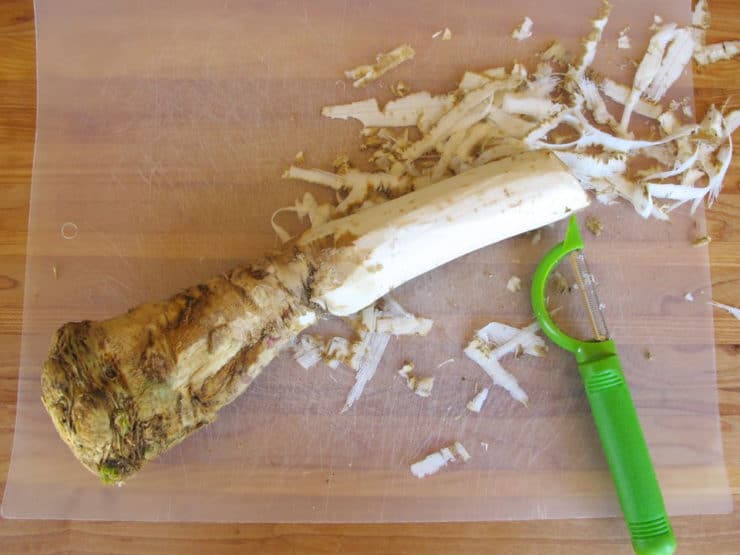 Peeling horseradish on a cutting board.
