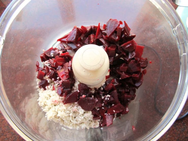 Chopped beets added to horseradish in a food processor.