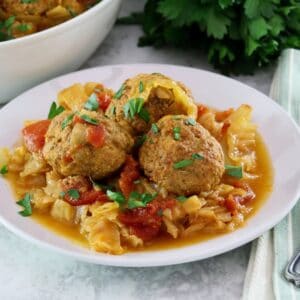 Horizontal image of a white bowl filled with "unstuffed cabbage". A bunch of fresh parsley sits in the back left corner.