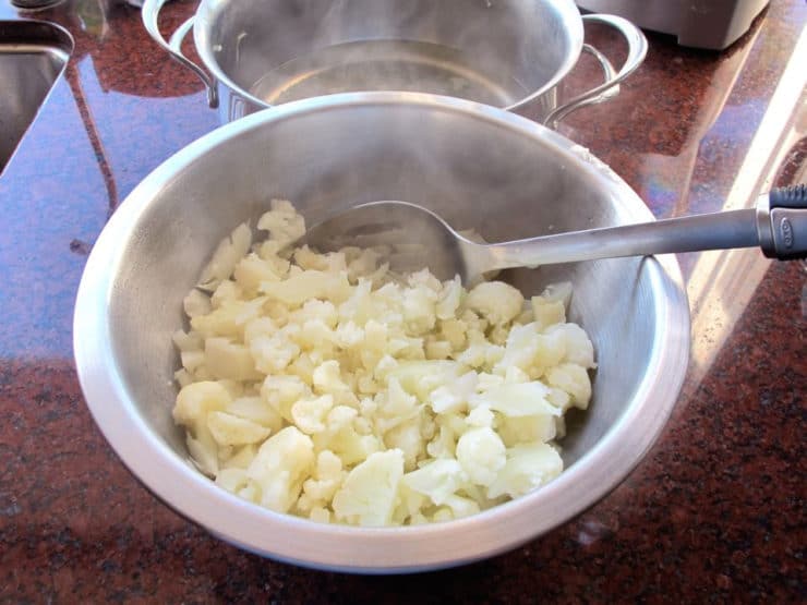 Draining cooked cauliflower.