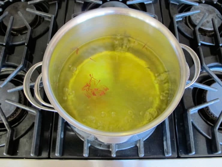 Simmering saffron threads in chicken broth.