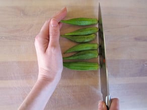 Lining up okra on a cutting board.