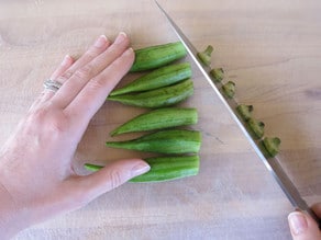 Chopping off stem end of okra.