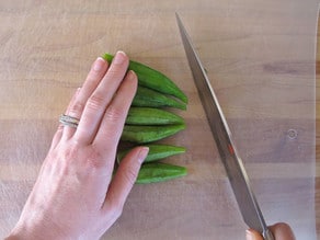 Chopping off pointy end of okra.