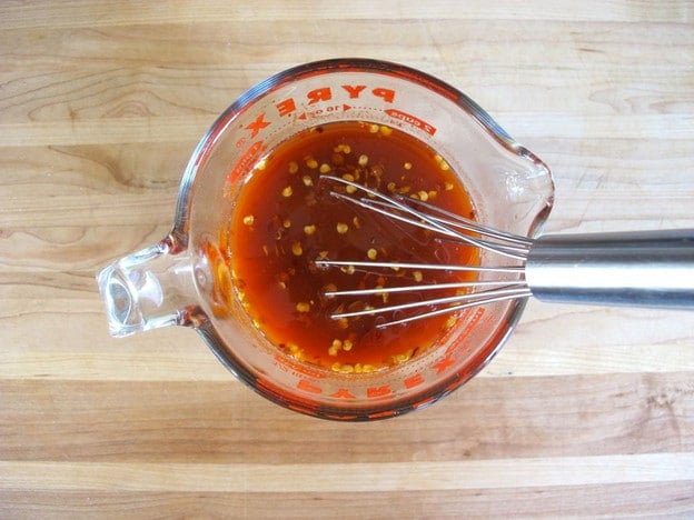 Whisking together tomato sauce in a measuring cup.
