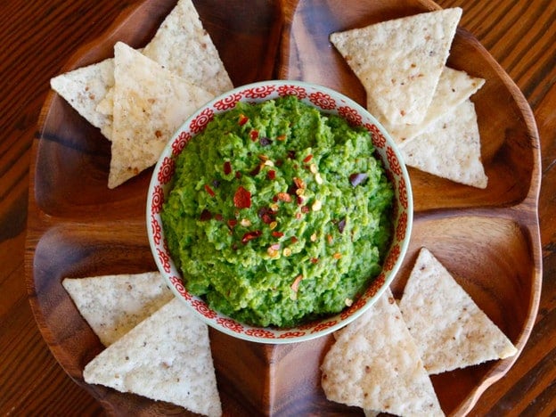 Overhead shot of Spring Pea Guacamole with nachos on sides