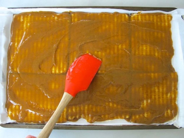 Spreading toffee evenly over matzo.