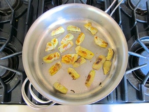 Browning artichokes in a saute pan.