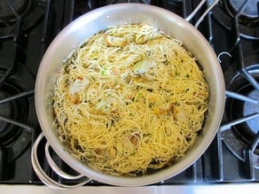 Stirring pasta into lemon butter sauce.