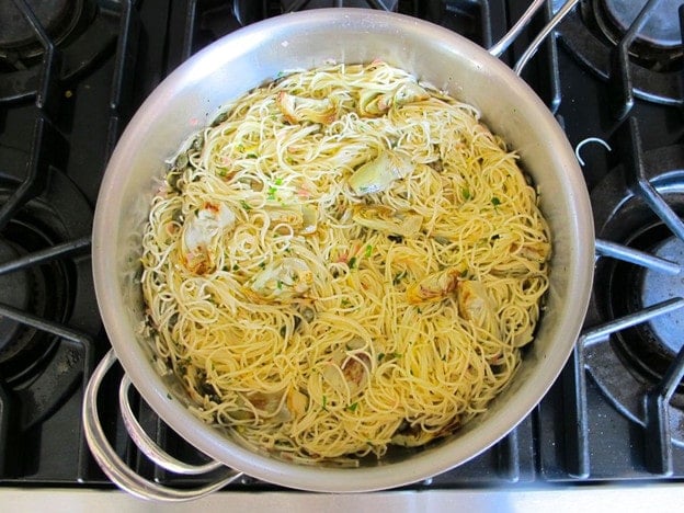 Stirring pasta into lemon butter sauce.