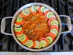Layering sliced vegetables around the edge of the saucepan.