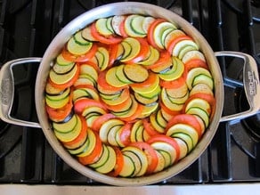 Continuing to layer sliced vegetables over the saucepan.
