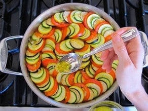 Spooning oil over layered ratatouille.