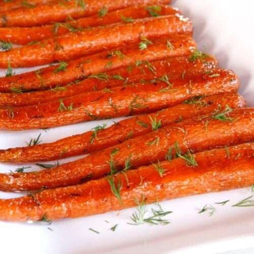 Close-up of Roasted Carrots with Dill lined and served on a white plate