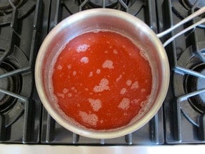 Simmering rhubarb syrup in a saucepan.