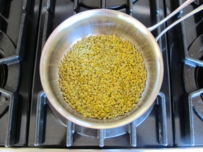 Toasting dry lentils in a saucepan.