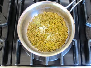Adding garlic to sauteeing lentils.